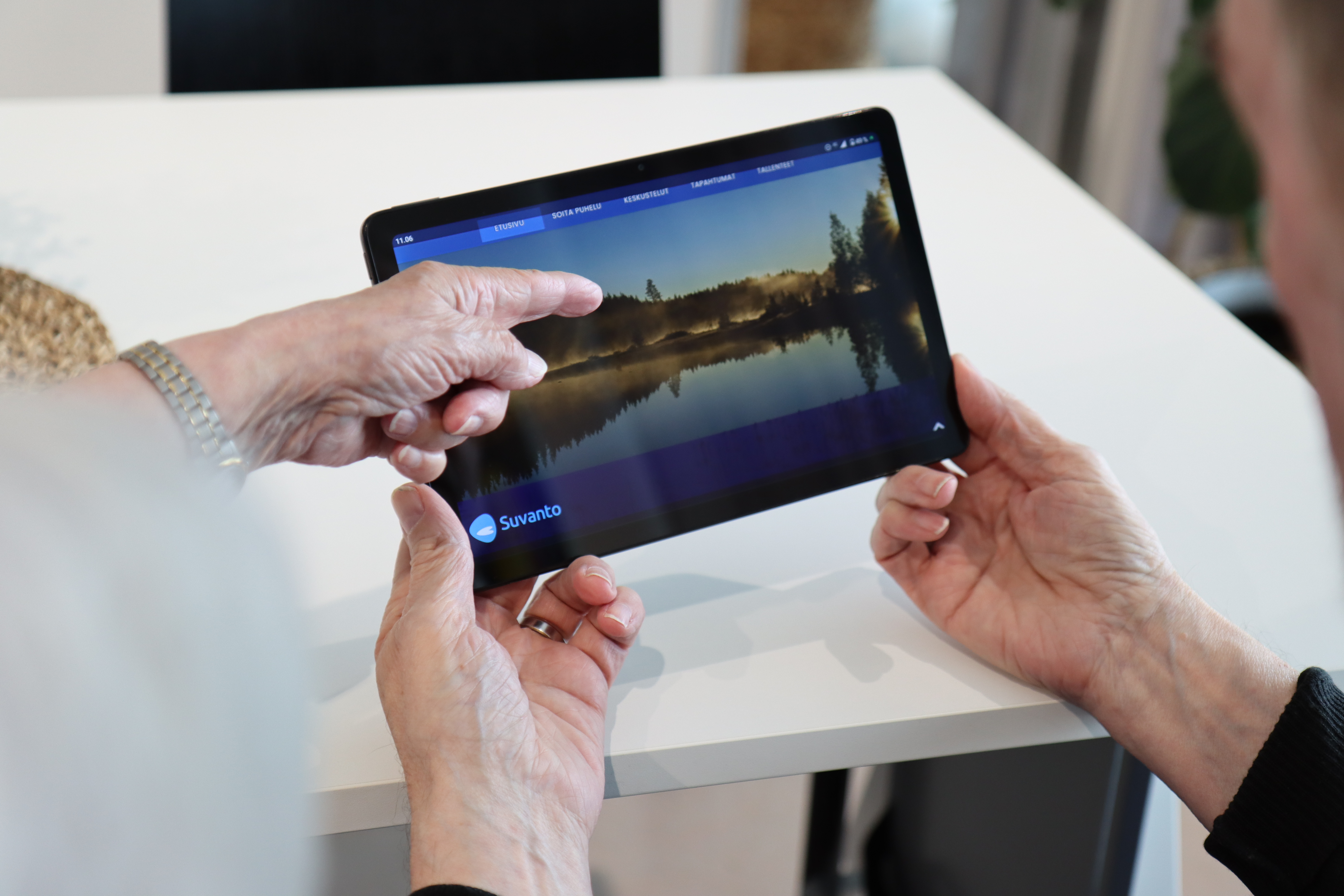 miehellä kädessä tabletti-tietokone ja toinen henkilö osoittaa sormella etusivua