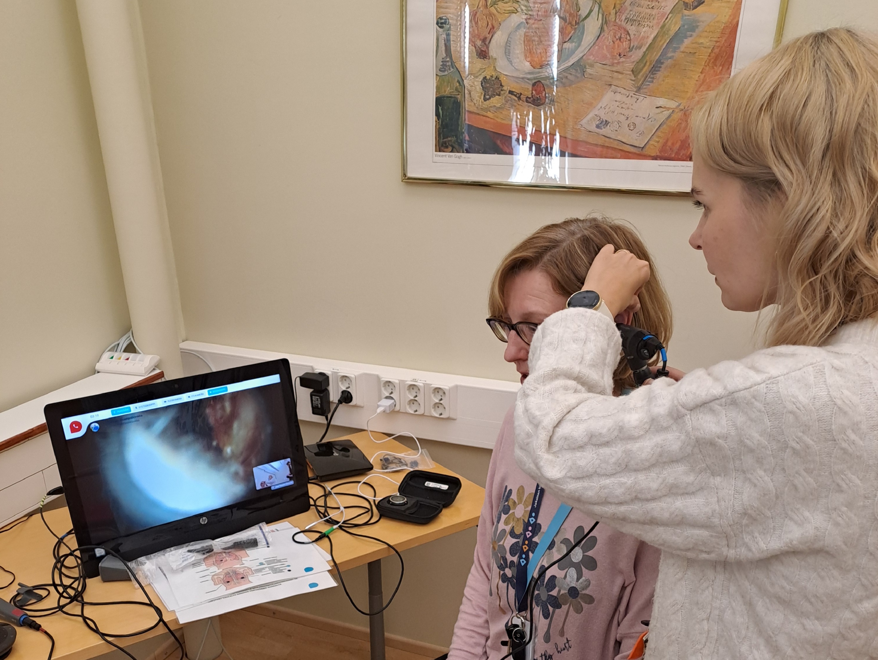 Hoitaja tutkii asiakkaan korvaa etädiagnotiikkavälineillä.