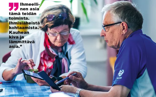 Nainen ja mies katsovat kumpikin älypuhelintaan pöydän ääressä.