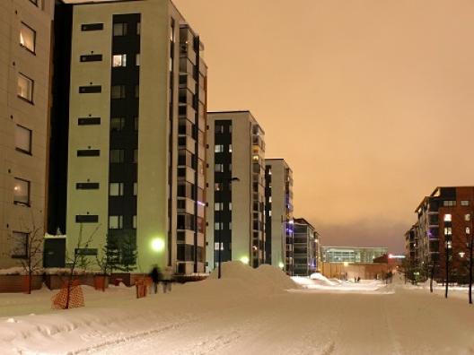 Kuvassa luminen katu kerrostalojen välissä. 