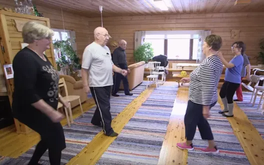 Ikäihmiset jumppaavat ryhmänä kodin olohuoneessa