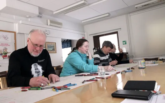 Vertaisryhmään osallistujat keskittyvät musiikin kuunteluun ja piirtämiseen.