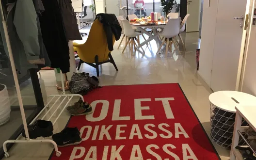Kuvassa näkyy Propellipäiden työtilan eteinen, jossa on punainen matto, jossa lukee "olet oikeassa paikassa".