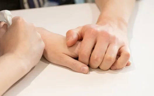 Kaksi ihmistä pitävät toisiaan kädestä kiinni.