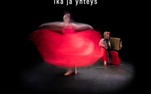 Kuvassa tanssija pyörii punaisessa mekossa ja taustalla näkyy harmonikan soittaja