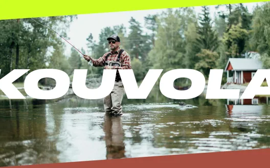 Kouvolan kaupungin logo maisemakuvan päällä, jossa mies kalastaa joessa ja taustalla näkyy punainen puinen mökki.