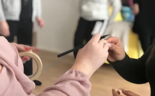 Kuvassa etualalla kaksi nuorta, jotka välittävät paperin toisilleen. Taustalla näkyy sumeasti muita nuoria. 