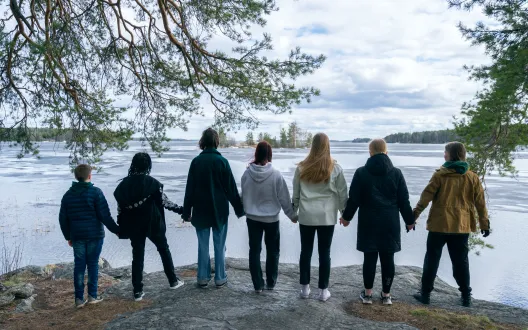 Nuoret seisovat rannalla käsi kädessä