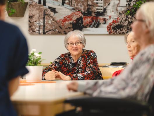 Ikääntyneet keskustelevat pöydän äärellä