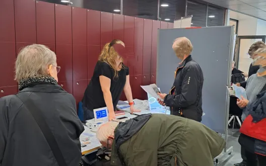 Tapahtuman kävijät tutustuvat Ikäteknologiakeskuksen esittelypöytään messulla.