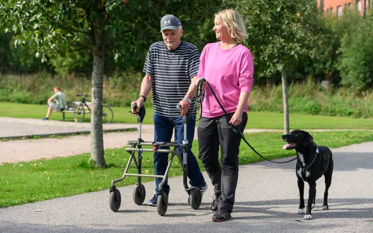 Ulkoiluystävä koirineen ulkoilemassa ikäihmisen kanssa