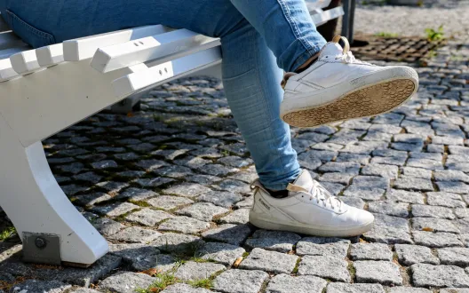 Puiston penkillä istuvan henkilön jalat ja kengät näkyvät kuvassa