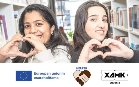 Kaksi maahanmuuttanutta muodostaa käsillään sydämen ja katsoo hymyillen kameraan
