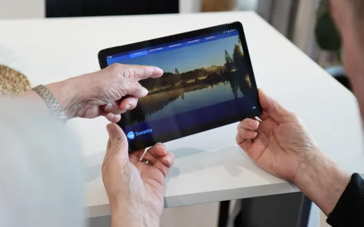 miehellä kädessä tabletti-tietokone ja toinen henkilö osoittaa sormella näyttöä