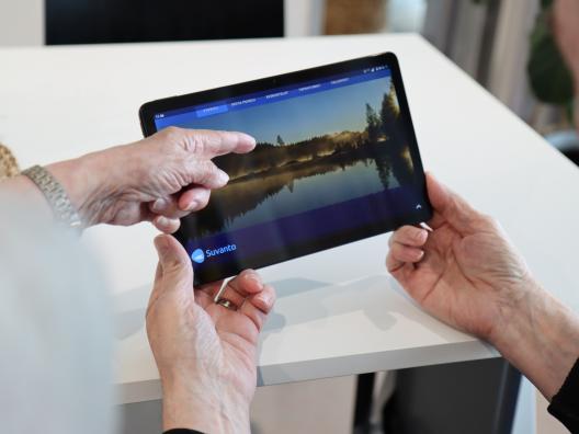 miehellä kädessä tabletti-tietokone ja toinen henkilö osoittaa sormella näyttöä