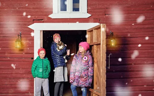 Lapset seisovat punaisen rakennuksen ulko-ovella.