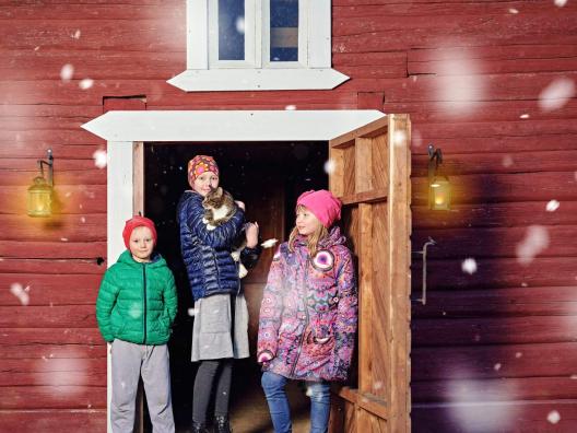 Lapset seisovat punaisen rakennuksen ulko-ovella.