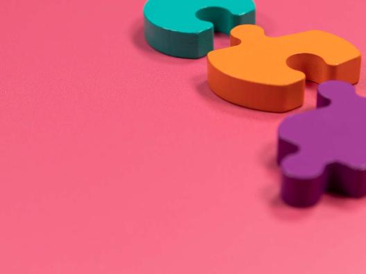 Pinkillä pohjalla kolme eri väristä palapelin palaa.