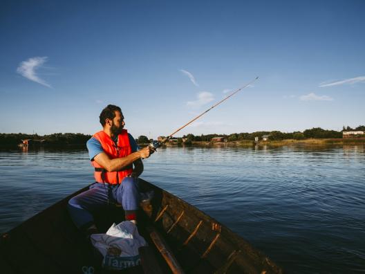 Mies kalastaa järvellä.