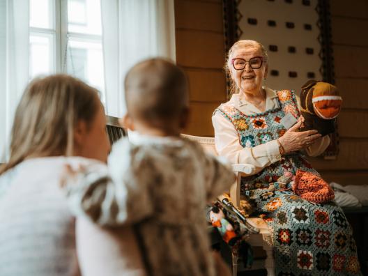 Mummo kertoo tarinaa taaperoperheelle.