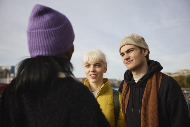 Yksi henkilö selin ja kaksi henkilöä kasvot näkyvissä.