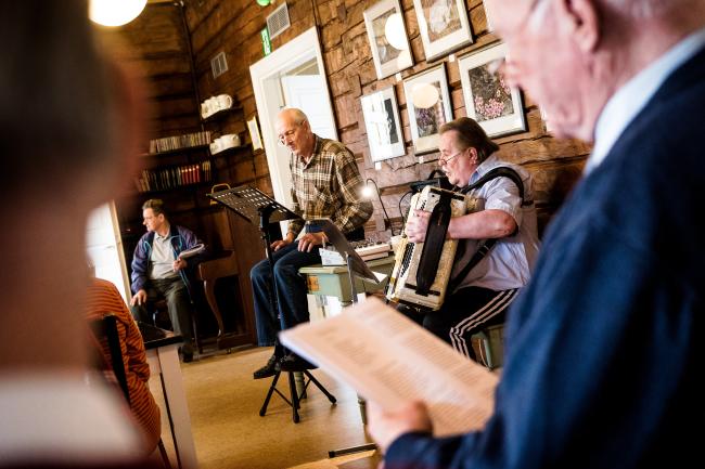 Singsongs in the Lähteentien Pirtti, old building. Old male singing, old male playing accordion.