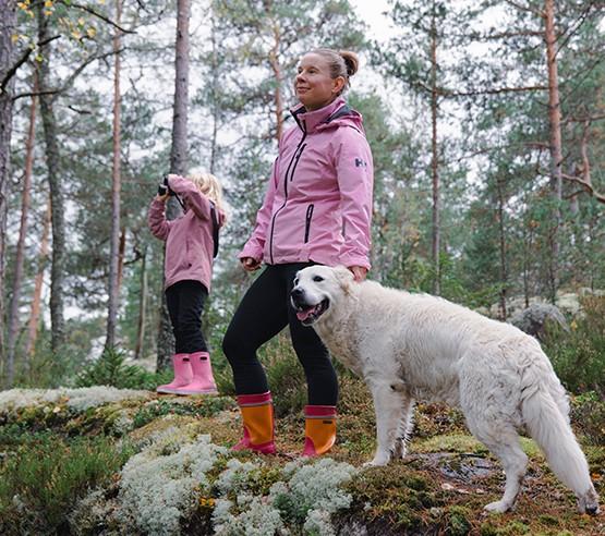 Nainen, lapsi ja koira luonnossa. Kuvituskuva