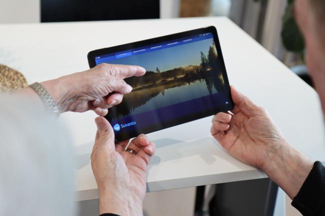 miehellä kädessä tabletti-tietokone ja toinen henkilö osoittaa sormella näyttöä