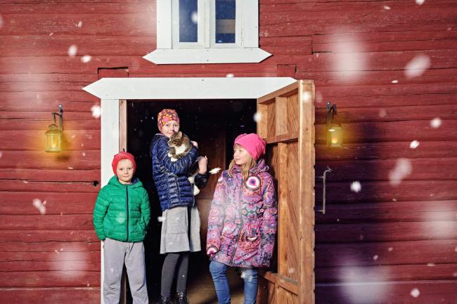 Lapset seisovat punaisen rakennuksen ulko-ovella.