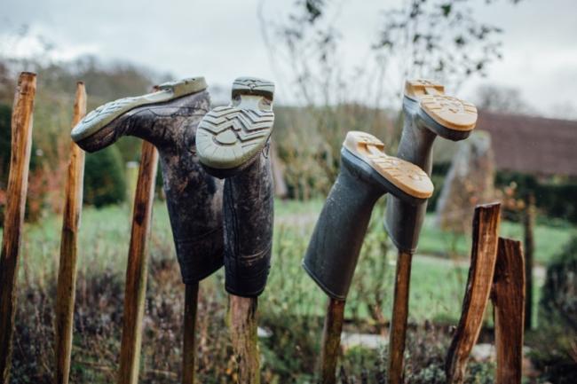 Kahdet mutaiset saappaat kuivumassa tikun nokassa pellon laidalla