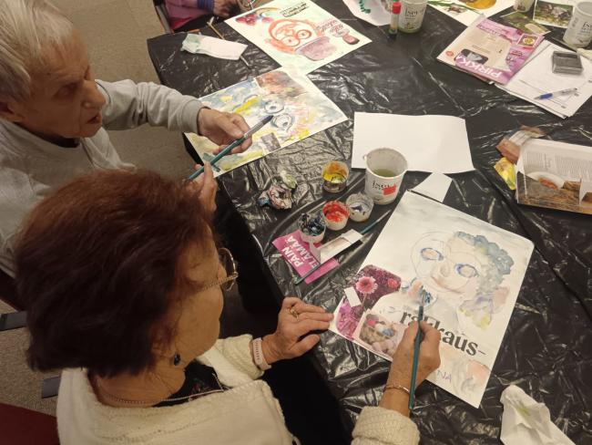 Kuvassa ikääntynyt pariskunta tekee kollaasityötä mm. akvarelleilla, lehtileikkeillä.